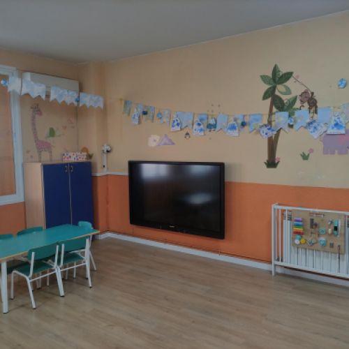 Aula con pantalla grande en pared y mesa rectangular con varias sillas