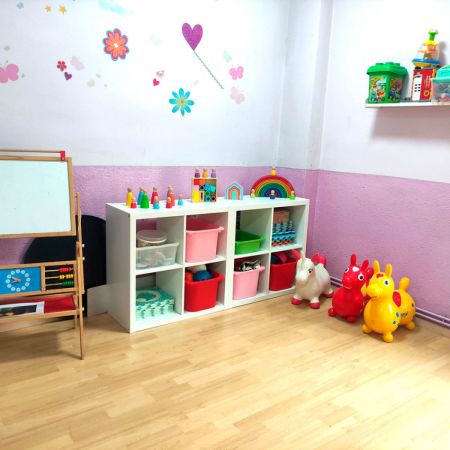 Imagen de aula con estantería blanca de madera y cajoneras de colores