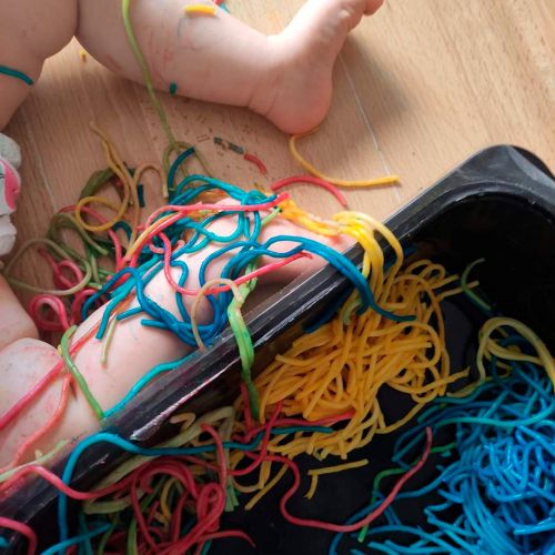 Piernas de bebé con espaguettis de colores