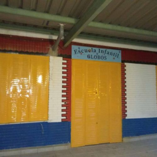 Entrada de la escuela con puertas y pared de color amarillo y azul