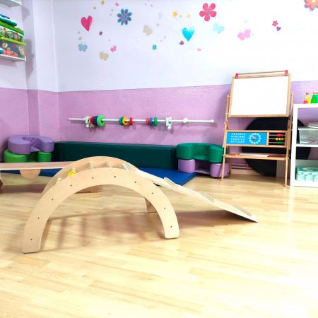 Aula con elementos de juego de madera y pared blanca y violeta