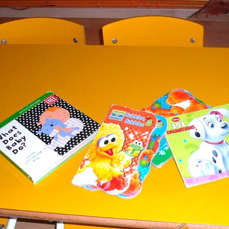 Mesa amarilla con cuatro sillas y varios cuentos sobre ella