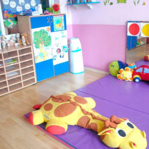 Aula grande con colchonetas de color morado y peluche grande amarillo