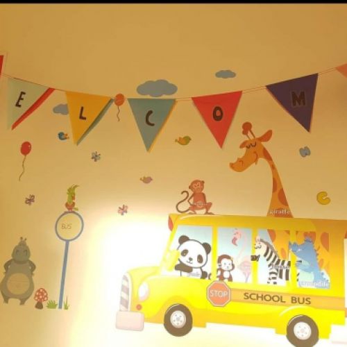 Pared en color crema con vinilos infantiles y banderines con texto de bienvenida
